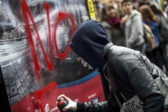 A masked student spray paints a poster during the protest.