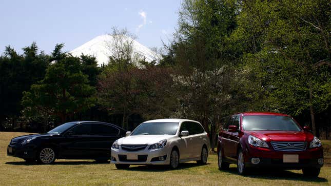 Three Subaru cars parked in a field 