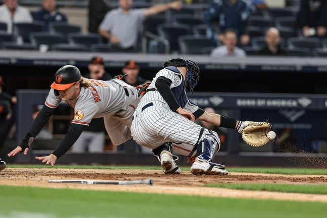 May 24, 2023; Bronx, New York, USA; Baltimore Orioles third baseman Gunnar Henderson (2) dives past New York Yankees catcher Kyle Higashioka (66) to score a run during the seventh inning at Yankee Stadium.