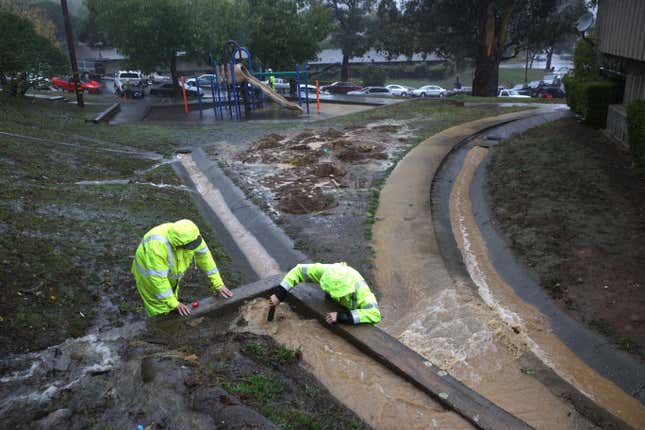 Workers try to divert water into drains as rain pours down on October 24, 2021 in Marin City, California.