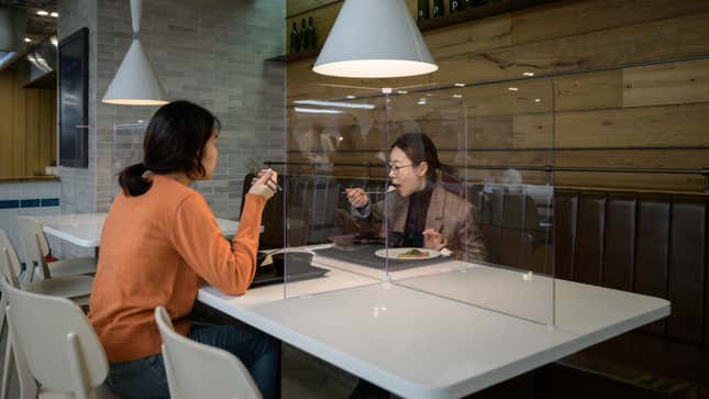 Employees sit behind protective screens as they eat in a cafeteria at the offices of Hyundai Card credit card company in Seoul, South Korea on April 9, 2020.