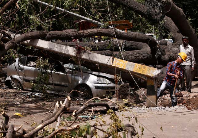 Electricity department workers remove damaged poles stuck under uprooted trees after a dust storm hit New Delhi on May 16, 2018.