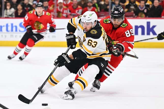 Mar 14, 2023; Chicago, Illinois, USA;  Boston Bruins forward Brad Marchand (63) skates in to steal the puck away from Chicago Blackhawks forward Andreas Athanasiou (89) in the third period at United Center.