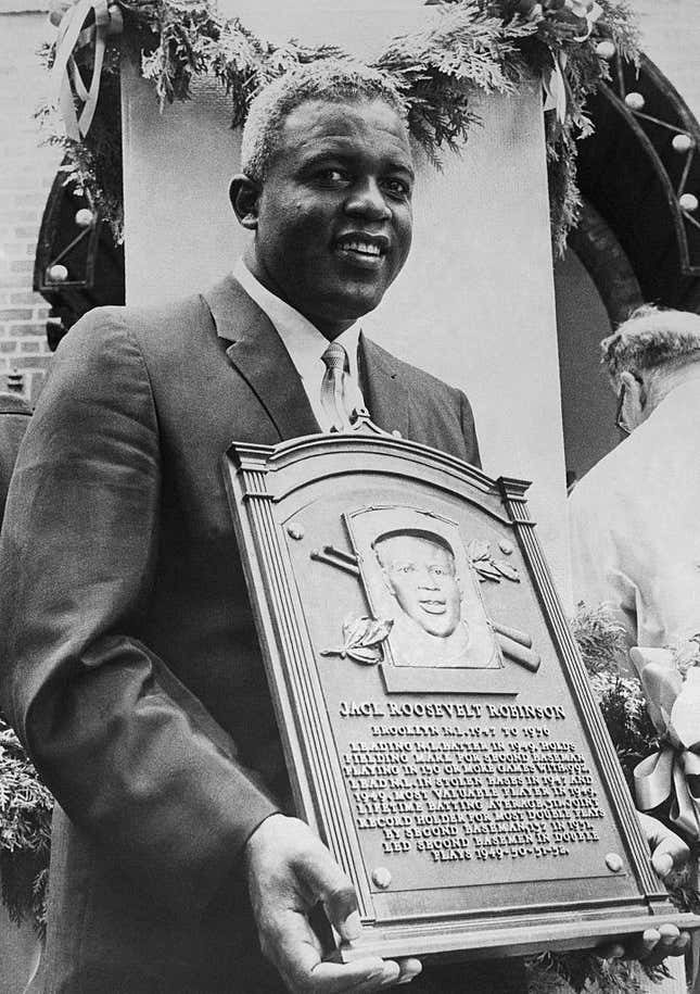 Smiling Jackie Robinson, who broke baseball’s color line in 1947, holds a plaque after he was inducted into baseball’s Hall of Fame here 7/23.