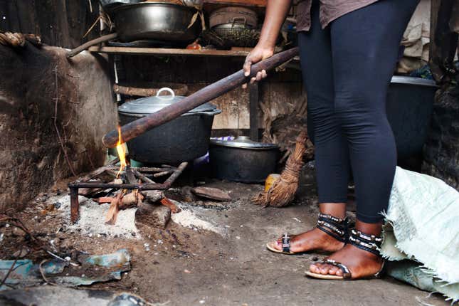 A survivor of breast ironing holds a stick used for breast ironing over a fire for a demonstration in Douala, Cameroon,