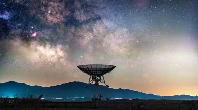 A satellite dish points upward at the visible Milky Way galaxy