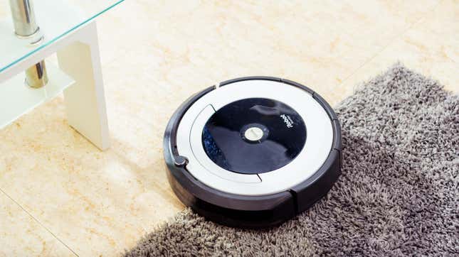 Una aspiradora Roomba Irobot limpia una alfombra gris.