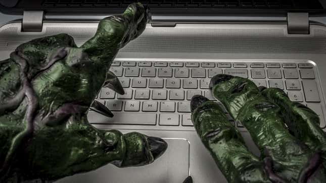 Goblin-like hands stretch out over a laptop's keyboard.