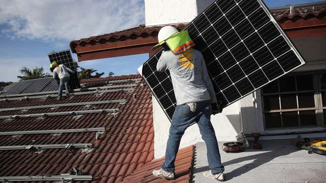 Workers install a solar panel system on the roof of a home in Palmetto Bay, Florida.