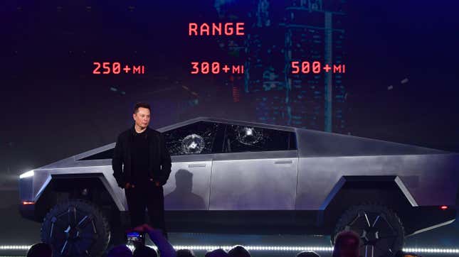 Elon Musk stands in front of a Cybertruck with two marks in the windshield where a person damaged them with a steel ball.