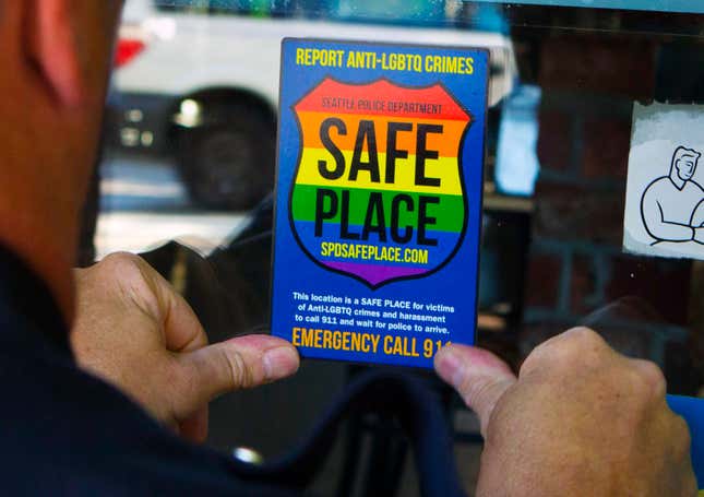 FILE - In this June 24, 2015 photo, Officer Jim Ritter places a &quot;Safe Place&quot; sticker on the window of a business in Seattle&#39;s Capitol Hill neighborhood. Some central Florida lawmakers said they are considering “all legislative, legal and executive options available” to stop business owners in a small town from voluntarily displaying rainbow decals in their windows indicating that they are “safe places” for LGBTQ people who feel threatened.(Ellen M. Banne/The Seattle Times via AP, File)