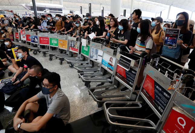 Anti-government protesters stand at a barricade made of trolleys during a demonstration at Hong Kong airport, Aug. 13, 2019.