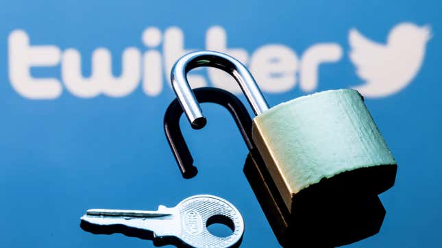 An open security lock and key on the background of the Twitter social network logo in the mirror reflection.