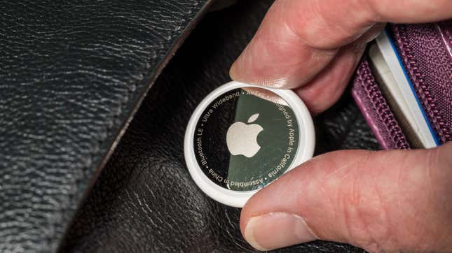 A hand placing an Apple AirTag into the fold of a wallet.