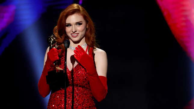 Kaitlyn “Amouranth” Siragusa, in a red dress, is accepting the Favorite Creator Site Star award at the January 2023 Adult Video News Awards ceremony in Las Vegas.