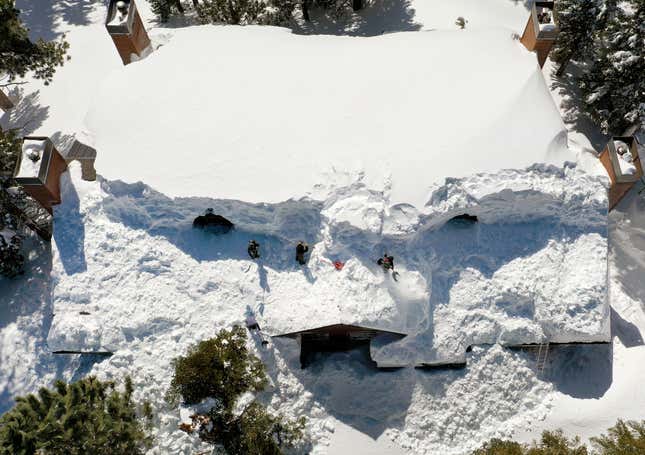 Workers dig out a condominium roof covered in snow in Mammoth Lakes, CA.