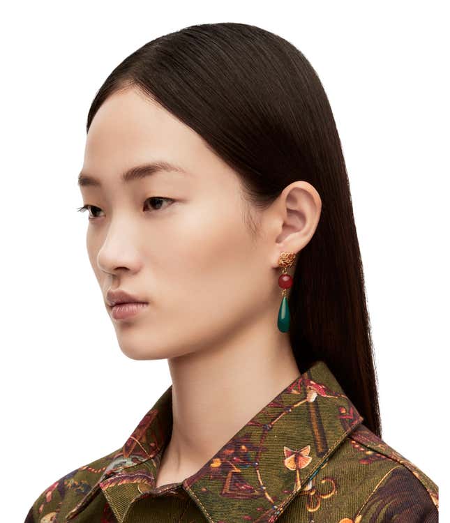 Earrings with a golden clasp, a red bead, and a green teardrop.