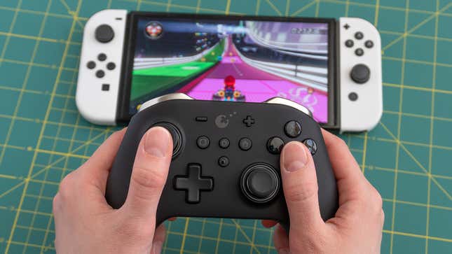 Photo of a GuliKit KingKong Pro 2 controller and a Nintendo Switch OLED