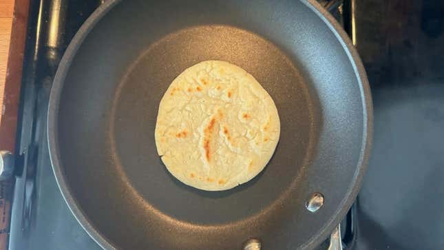 Arepa cooking in a pan.