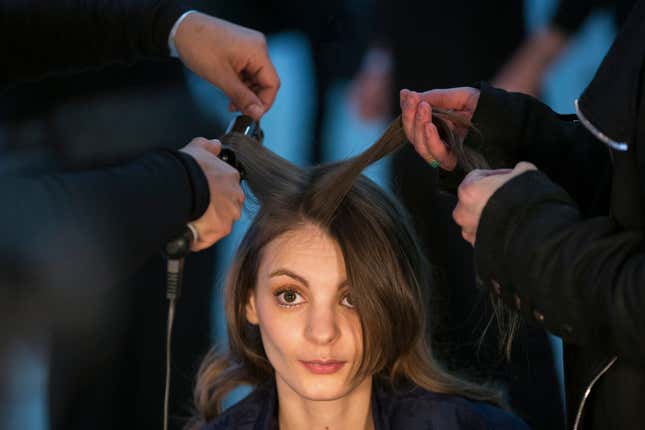 A model has makeup applied and her hair done backstage before the Rodarte Fall/Winter 2015 collection show.