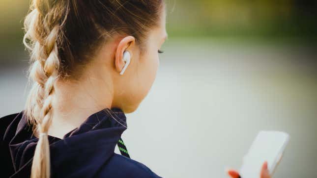 Young woman wearing airpods and holding a smartphone