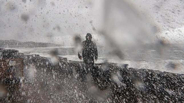 Waves and water crash around a man in the middle of a storm in Oregon.
