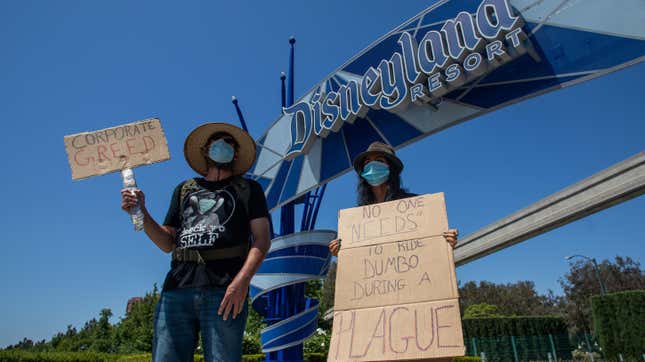 People holding signs in front of Anaheim’s Disneyland as part of a cast member unions protest against reopening without on-demand covid-19 testing. 