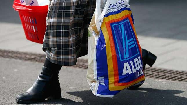 Person carrying Aldi bag out of store with basket