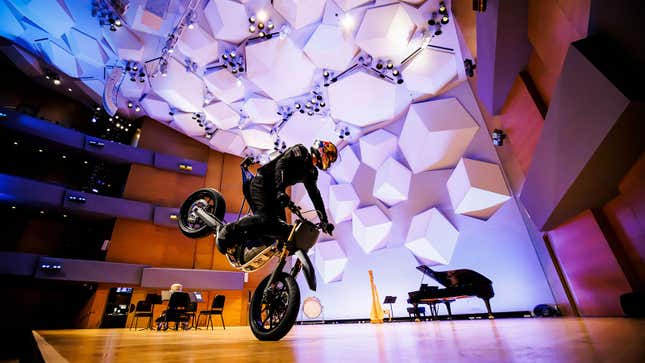 Photo of Aaron Colton riding a motorcycle on stage. 