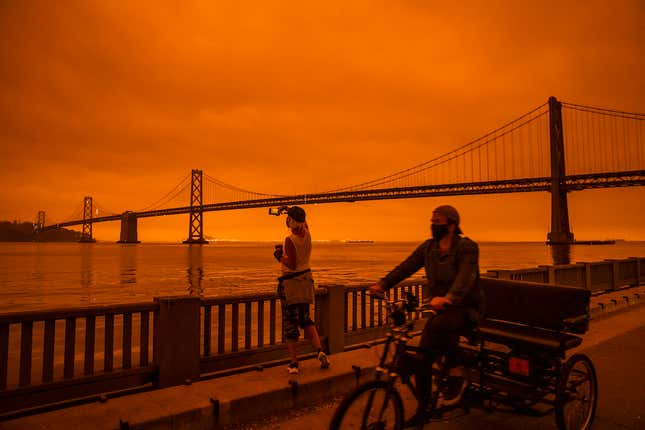Amy Scott of San Francisco takes in the view from the Embarcadero as smoke from various wildfires burning across Northern California mixes with the marine layer, blanketing San Francisco in darkness and an orange glow on Sept. 9, 2020, in San Francisco, California. 