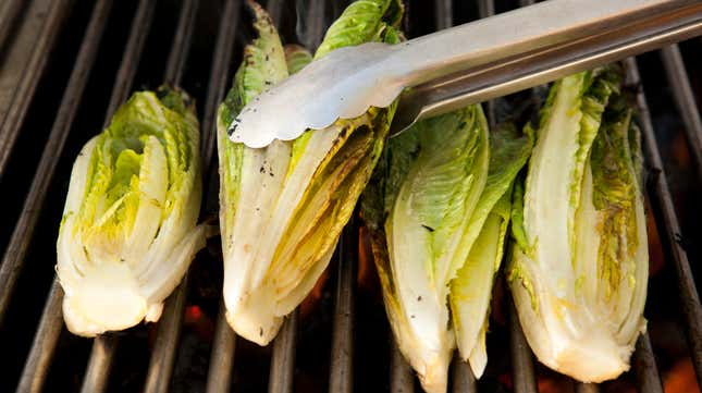 Tongs turning romaine hearts on the grill