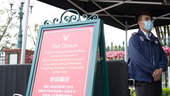 A member of staff wearing a mask stands next to a sign announcing the park’s closure at Hong Kong Disneyland in Hong Kong on January 26, 2020,