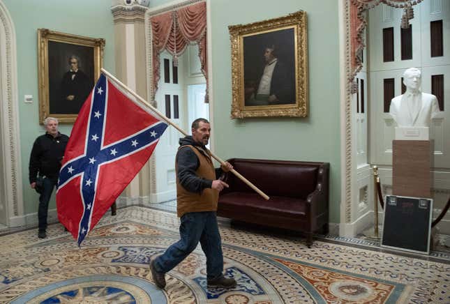 A supporter of US President Donald Trump carries a Confederate flag as he protestS in the US Capitol Rotunda on January 6, 2021, in Washington, DC. - Demonstrators breeched security and entered the Capitol as Congress debated the a 2020 presidential election Electoral Vote Certification.