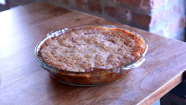 Whole apple pie in glass dish on wooden tabletop