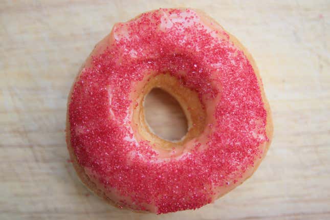 A ghost pepper donut covered in pink frosting and red sprinkles