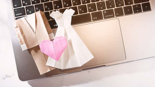Paper dolls of a bride and groom on a laptop keyboard