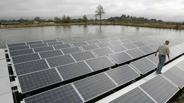 A man walks between floating solar panels on a pond in Oakville, California.