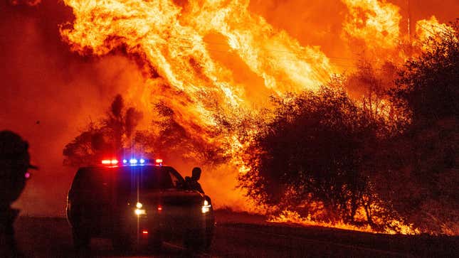 A law enforcement officer watches flames launch into the air as fire continues to spread during the Bear fire in Oroville, California on September 9, 2020. Dangerous dry winds whipped up California’s record-breaking wildfires and ignited new blazes, as hundreds were evacuated by helicopter and tens of thousands were plunged into darkness by power outages across the western United States. 