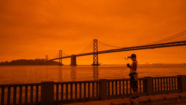 A runner takes a picture of the Bay Bridge in San Francisco under smoke-clogged skies.