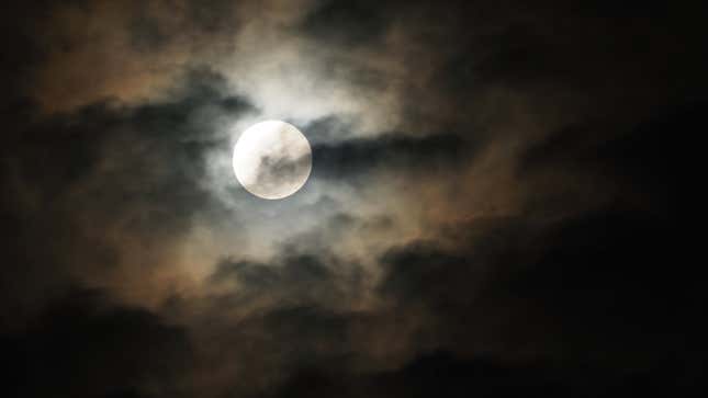 The full moon in a dark, cloudy night sky