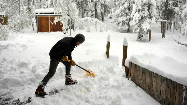 man shoveling snow in backyard