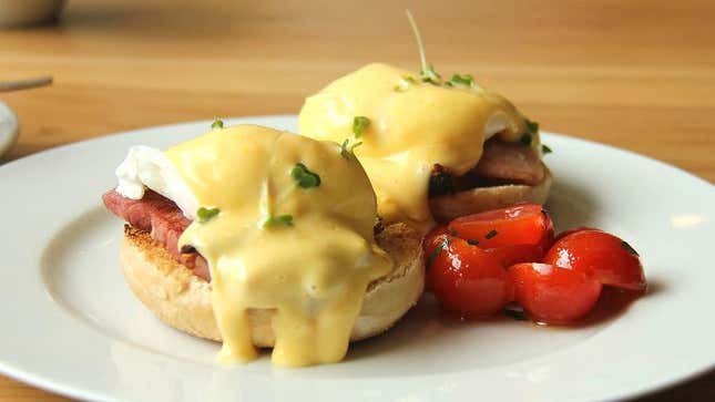 eggs benedict on a plate with grape tomatoes