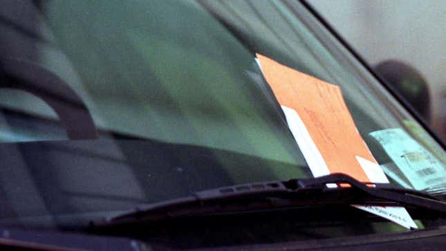 An orange parking ticket envelope under a windshield wiper