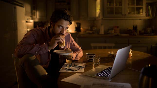 Man eating a burrito while staring at a laptop
