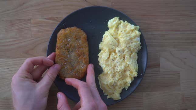 Hands holding hash brown on plate