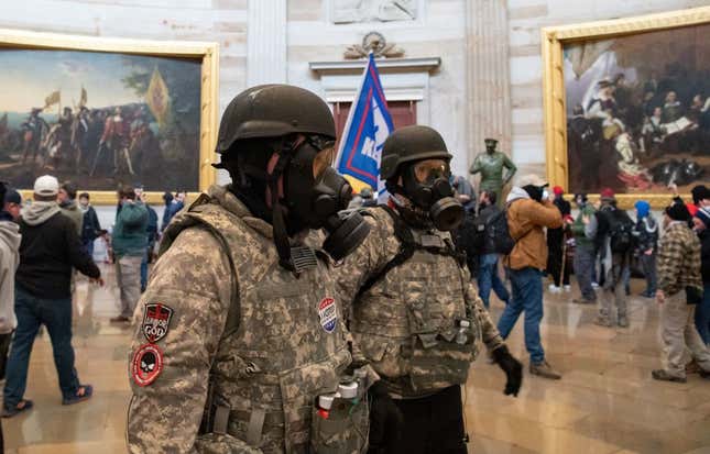 Supporters of US President Donald Trump wear gas masks and military-style apparel as they walk around inside the Rotunda after breaching the US Capitol in Washington, DC, January 6, 2021. - Demonstrators breeched security and entered the Capitol as Congress debated the 2020 presidential election Electoral Vote Certification. 