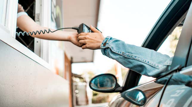person at drive through handing credit card machine to customer