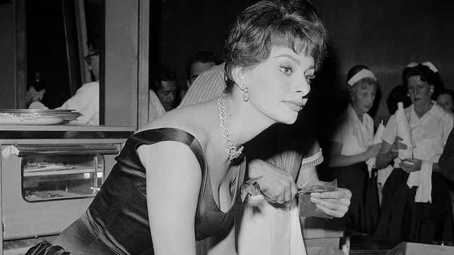 Sophia Loren leans over a table