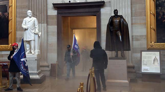 Violent extremists walk through a cloud of tear gas in the Capitol on Wednesday.