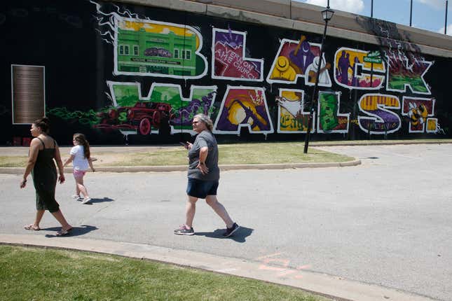 In this June 15, 2020, file photo, people walk past a Black Wall Street mural in the Greenwood district in Tulsa, Okla.